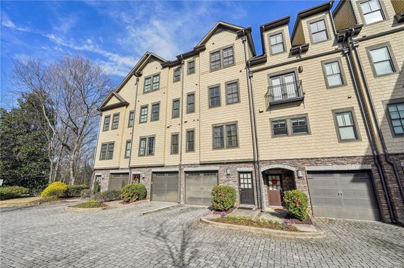 Front view of a multi-story townhouse with garage doors at the base.