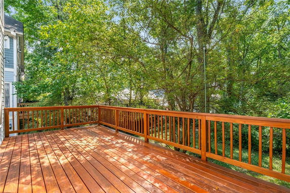 Wooden deck area adjacent to a house with surrounding trees.