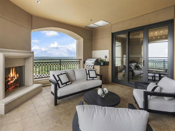 Outdoor terrace with fireplace, couches, and scenic view