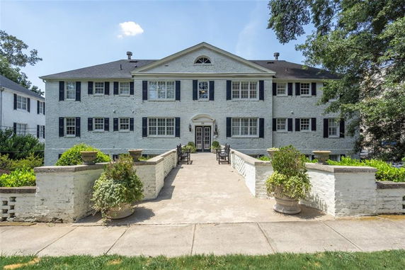 Front view of a large two-story brick house with multiple windows and a central entrance.