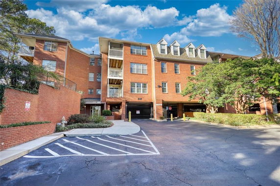 Front view of a multi-story brick building with balconies and dormer windows.