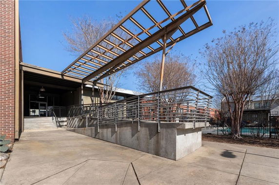 Front view of a building with a concrete ramp and metal railing leading to the entrance.