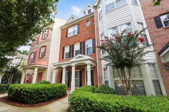 Front view of a multi-story townhouse with brick facade and white columns.