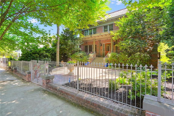 Front view of a two-story brick house with a gated entrance and surrounding trees.