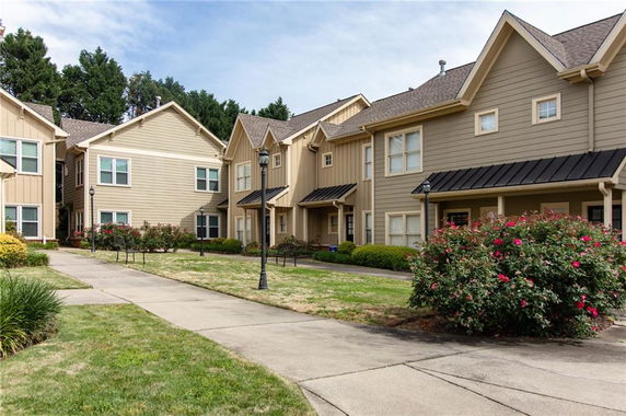 Front view of multiple two-story residential buildings with beige siding and gable roofs.