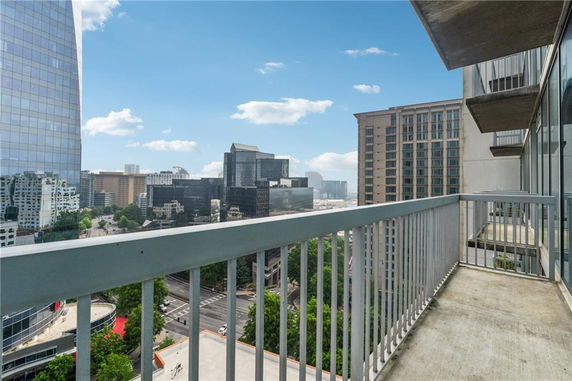 View from a balcony overlooking a cityscape with tall buildings and a clear sky.
