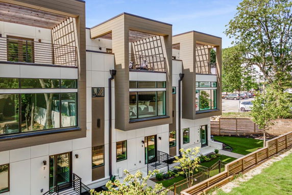 Front view of a modern multi-story building with large windows and wooden accents.
