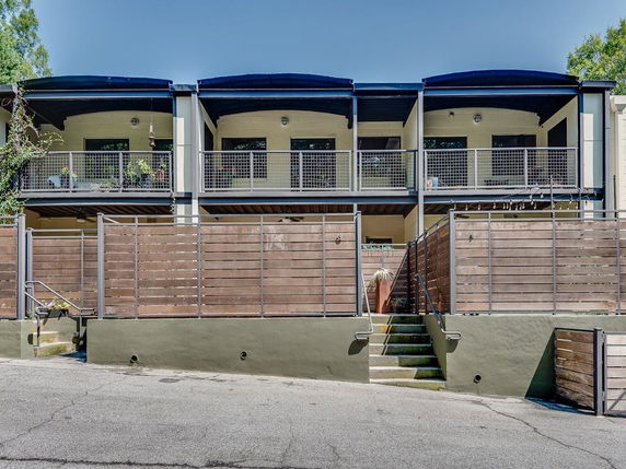 Front view of a two-story building with balconies and wooden fencing.