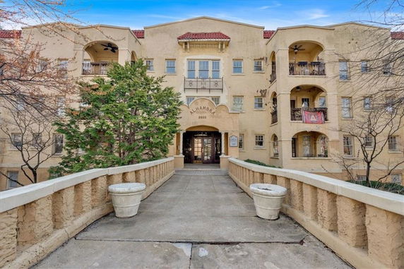 Front view of a multi-story building with arched balconies and a central entrance.