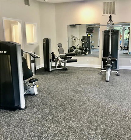 Indoor gym area with exercise machines and a large mirror.