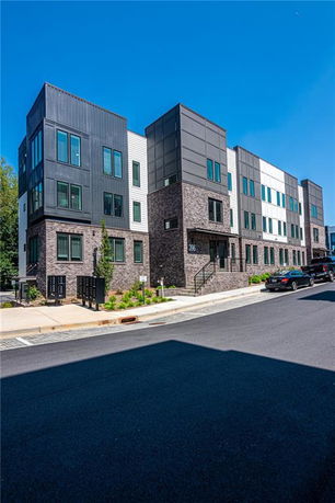 Front view of a modern multi-story apartment building with a combination of brick and panel exterior.