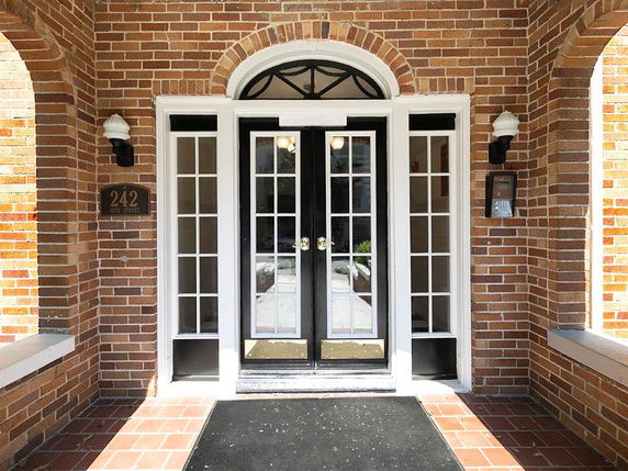 Front view of a building entrance with brick exterior and double doors.
