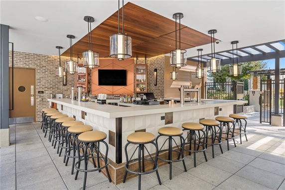 Modern indoor bar area with a central counter surrounded by stools and decorative lighting.