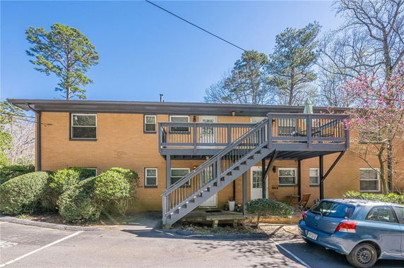 Front view of a two-story building with external staircase and parking area.