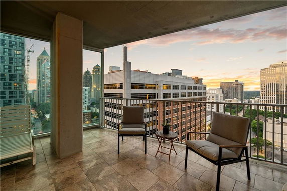Panoramic view from a balcony overlooking a cityscape with skyscrapers at sunset.
