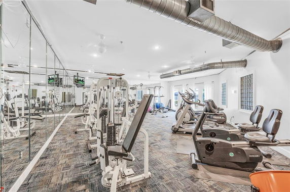 Interior view of a gym with exercise machines and mirrored walls.