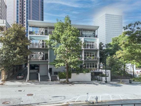 Front view of a modern multi-story building with balconies and large windows.