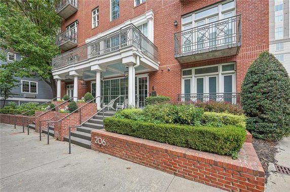 Front view of a brick building with balconies and an entrance staircase.