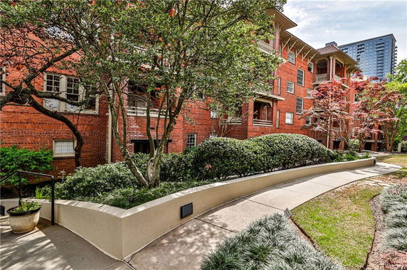 Front view of a multi-story brick building with landscaped pathway.