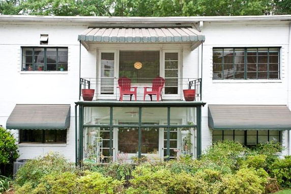 Front view of a two-story house with a balcony and large windows.