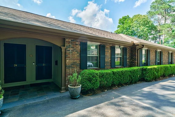 Front view of a single-story brick house with multiple entrances and decorative shutters.