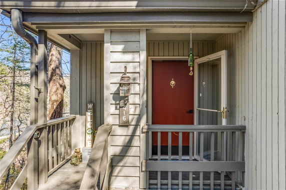 Front view of a house entrance with a red door and wooden railing.