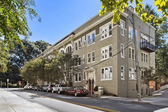 Front view of a multi-story apartment building with multiple windows and a small balcony.
