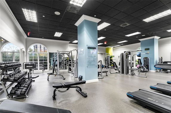 Interior of a gym with various fitness equipment including treadmills, weight racks, and exercise machines.