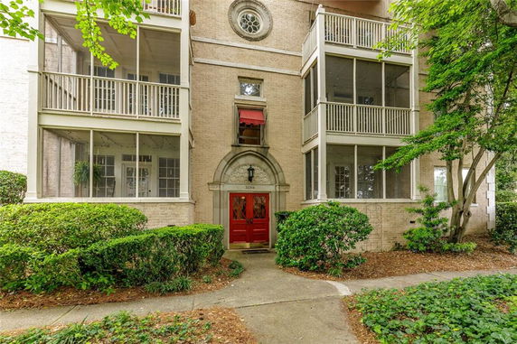 Front view of a multi-story building with screened balconies and a decorative red entrance.
