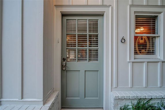 Front view of a house entrance with a light-colored door and nearby window.