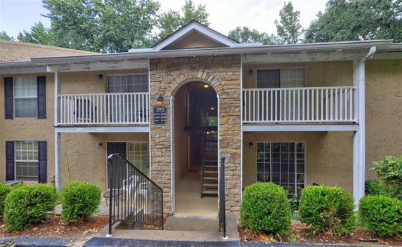 Front view of a two-story apartment building with stone arch entrance and balconies.