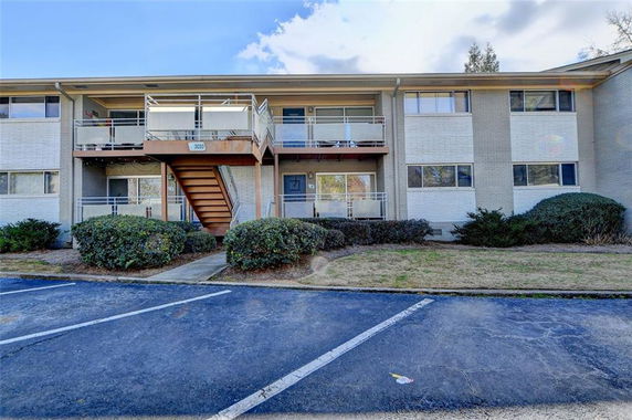 Front view of a two-story apartment building with balconies and a central staircase.