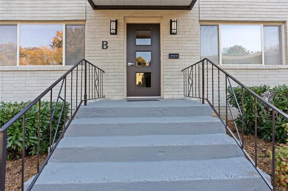 Front view of a building entrance with steps and black metal railing.