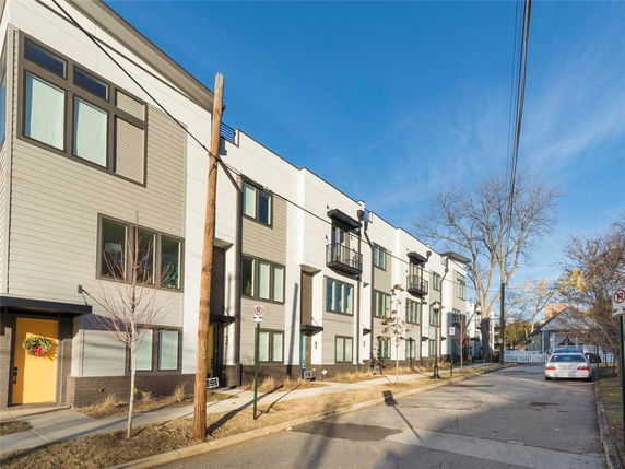 Front view of a modern multi-story apartment building with large windows and small balconies.