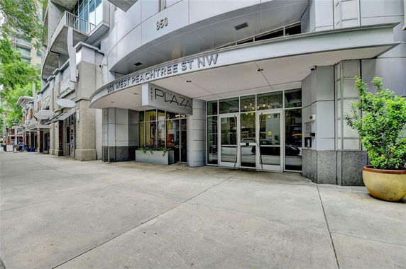 Front view of a modern building entrance with glass doors and potted plants.