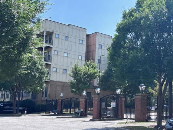 Front view of a multi-story apartment building with a gated entrance.