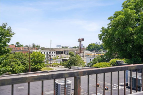 View from a rooftop with air conditioning units, overlooking nearby buildings and greenery.