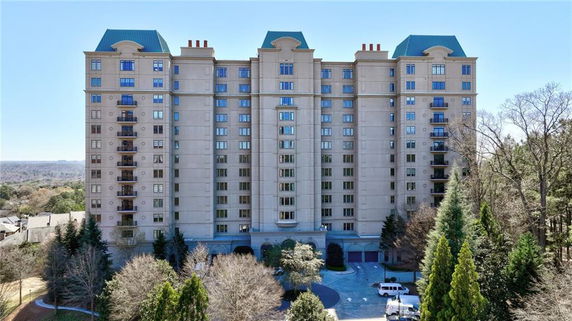 Front view of a multi-story residential building with a symmetrical design and blue roof accents.
