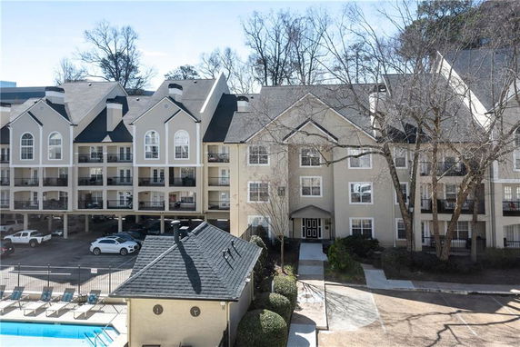 Front view of a multi-story apartment building with balconies and parking area.
