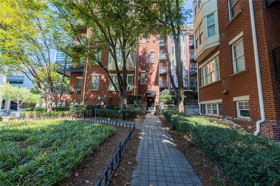 Front view of a multi-story brick building with multiple windows and an entrance pathway.