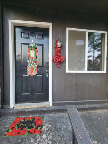 Front view of a house entrance with a decorated door and a welcome mat.