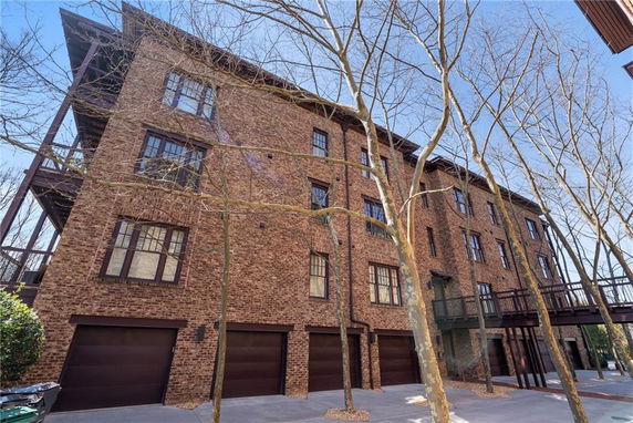 Front view of a multi-story brick building with multiple garages and elevated walkway.