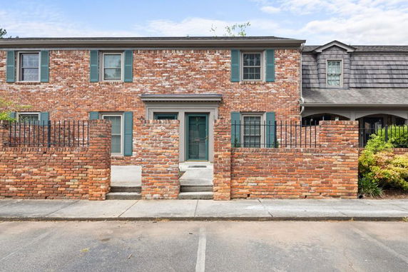 Front view of a two-story brick house with a central entrance and windows with shutters.