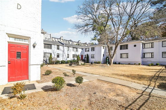 Front view of a two-story apartment building with red doors and white exterior.