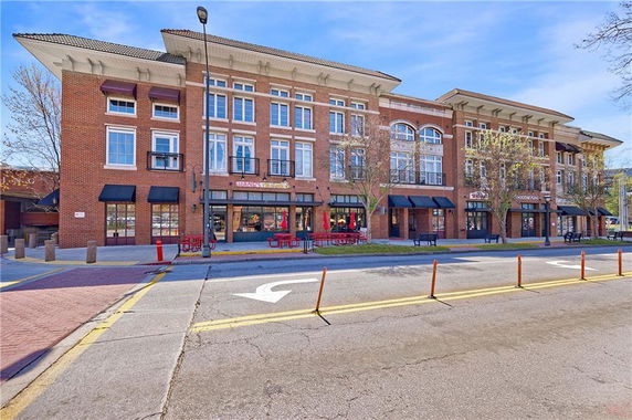 Front view of a multi-story brick building with commercial spaces on the ground floor.
