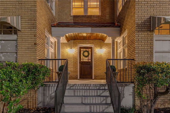 Front view of a two-story brick house with a central entryway and porch lighting.