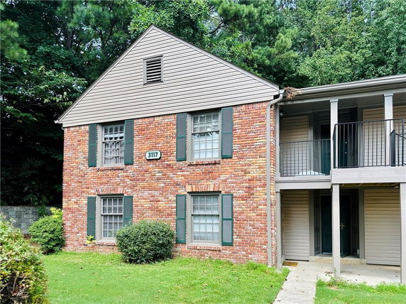 Front view of a two-story brick house with green shutters.