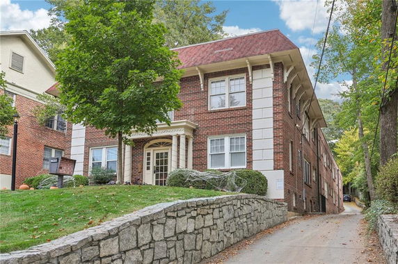 Front view of a two-story brick building with a decorative entrance and a sloped driveway.