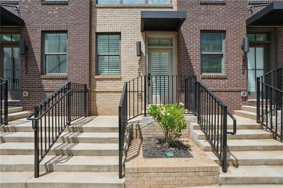 Front view of a brick townhouse with steps and railing.