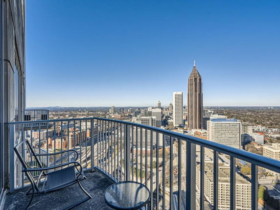 Balcony with chairs overlooking a city skyline and high-rise buildings.